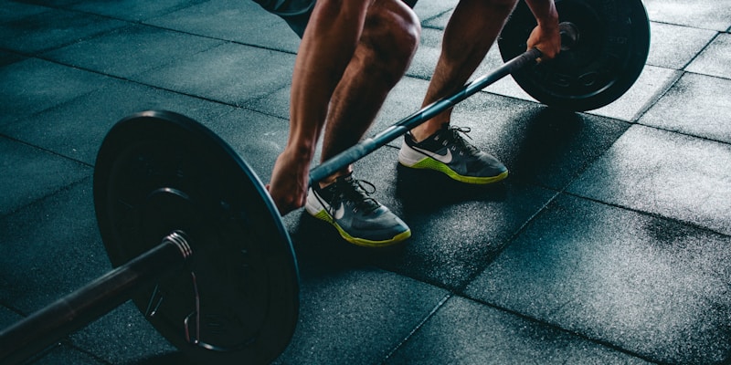 Person performing strength training with barbell in gym